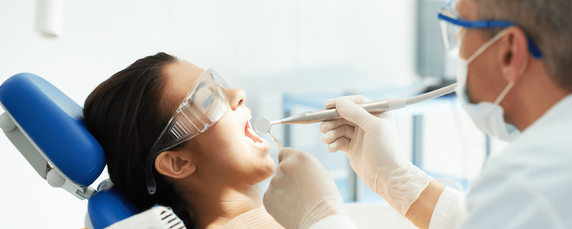 Tannlege med utstyr som behandler en pasient.